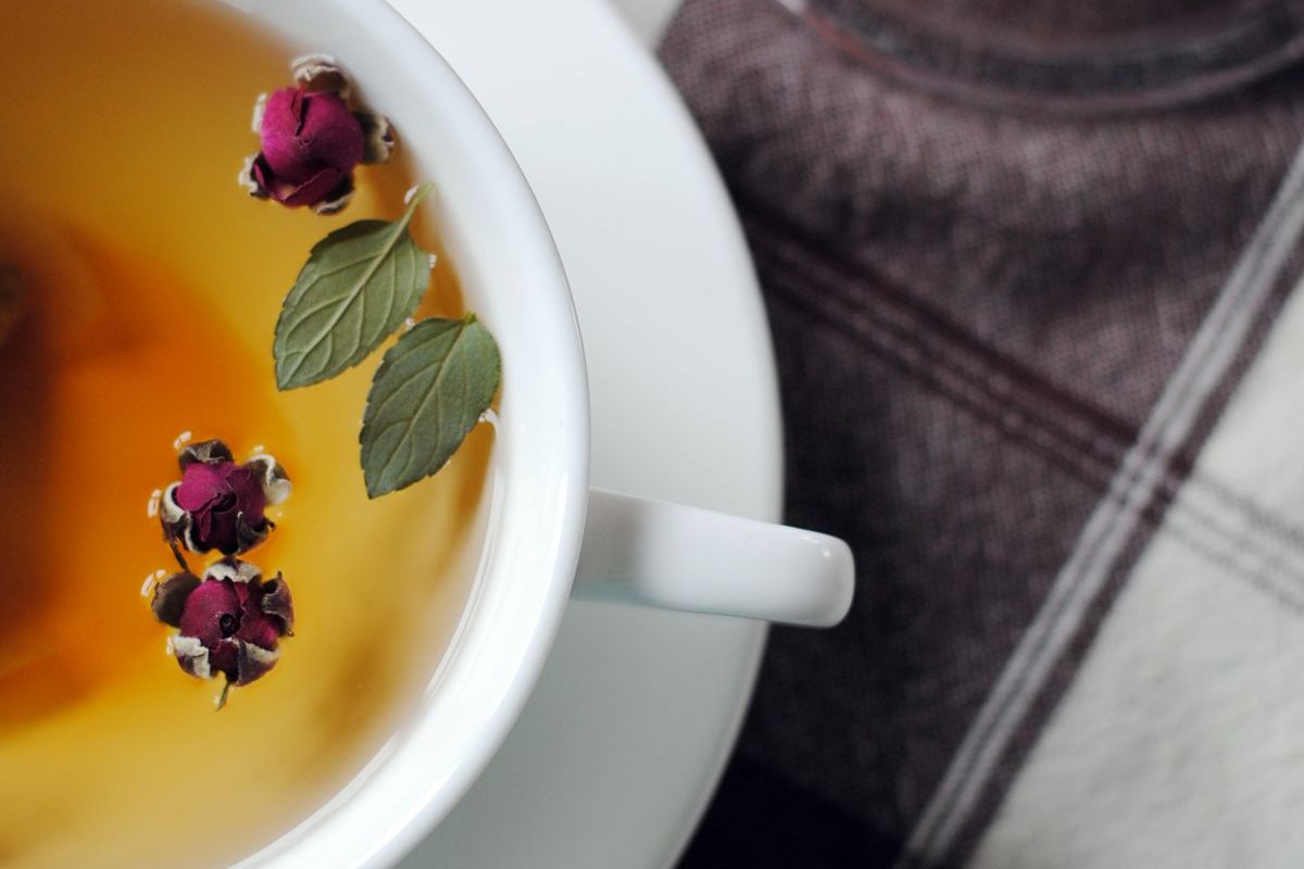 A cup of herbal tea with rosebuds and mint leaves — natural remedies used in homeopathy